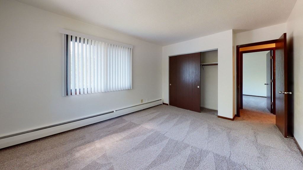 an empty living room with a window and a door to a closet