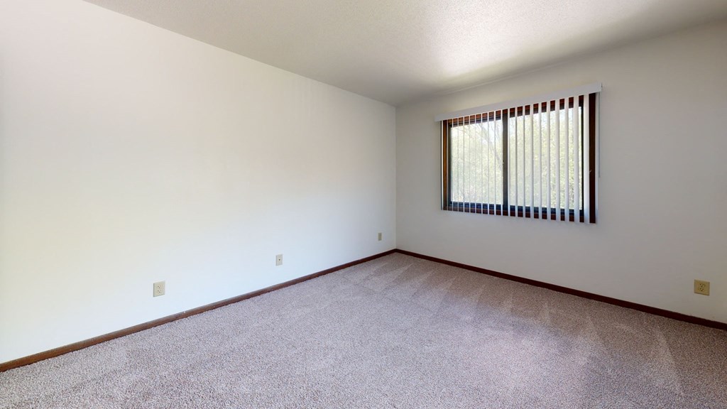 a spacious living room with carpet and a window