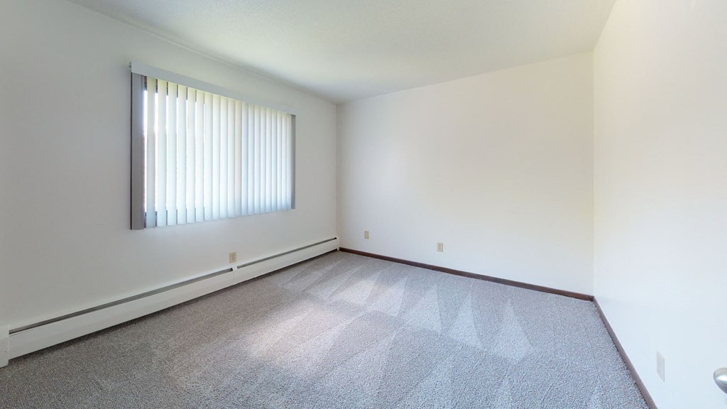 an empty room with a window and a carpeted floor