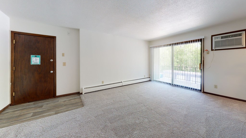 an empty living room with a door to a balcony