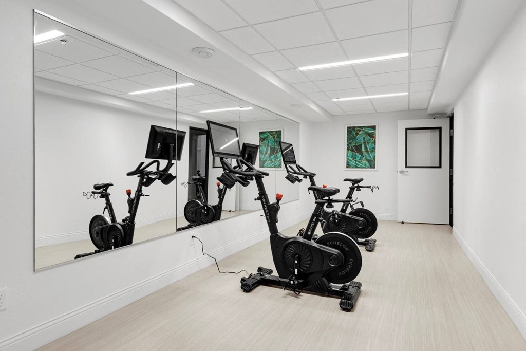 a gym with several exercise bikes in a white room