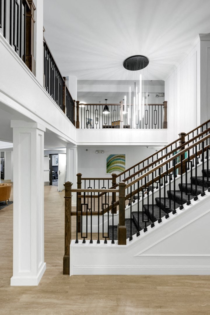 a sweeping staircase in the middle of a house with white walls and wood floors