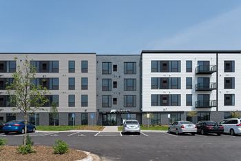 A parking lot in front of a modern apartment building.