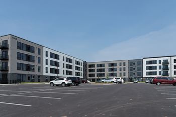 A parking lot in front of a multi-story apartment building.