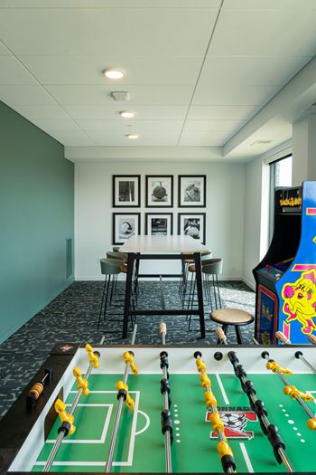 A foosball table is in the middle of a room with a bar and chairs.