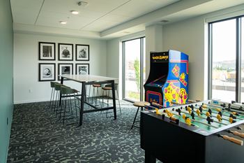 A foosball table is in the middle of a room with a bar and chairs.