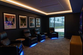 A room with black leather chairs and pictures on the wall.