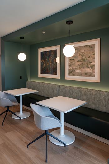 A room with a green wall and a white table and chairs.