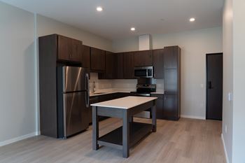 A kitchen with a refrigerator, microwave, oven, and sink.
