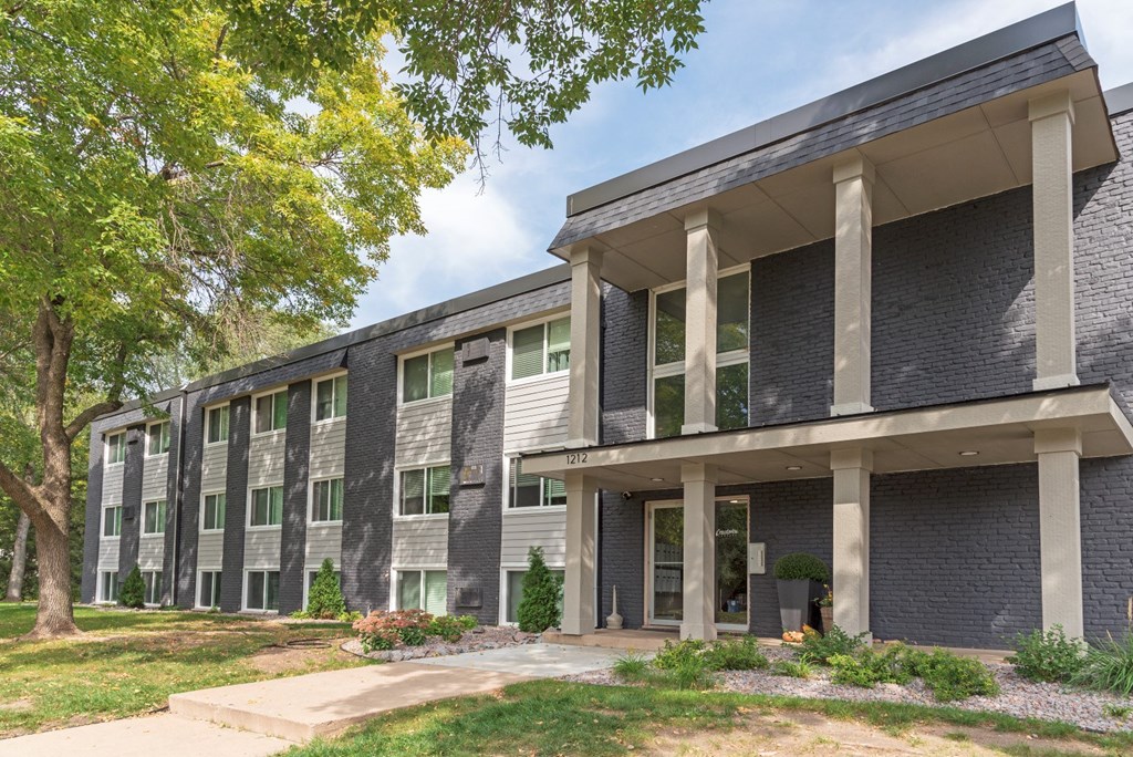 the front of a building with trees and grass