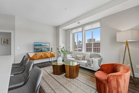 A living room with a grey couch, a red chair, and a painting on the wall.