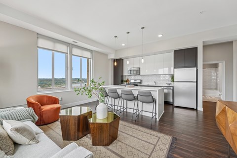 A modern living room with a kitchen in the background.