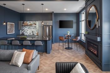 A modern living room with a grey sofa and a fireplace.at The Edison at Maple Grove, Maple Grove