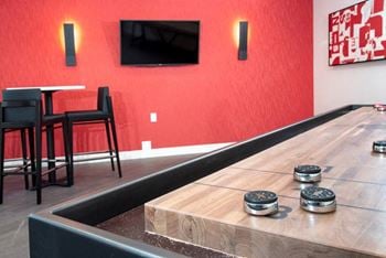 Game Room With Shuffleboard, Red Walls, Seating, and Modern Decor at Eagan Place Apartments