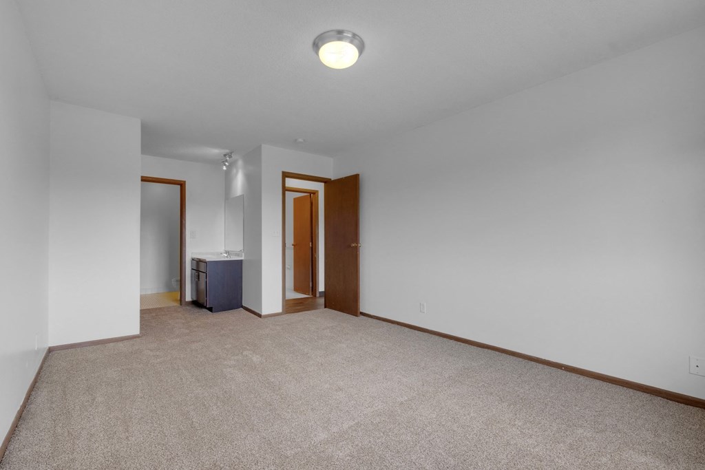 a bedroom with white walls and a beige carpet