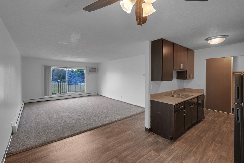 an empty living room and dining room with a ceiling fan