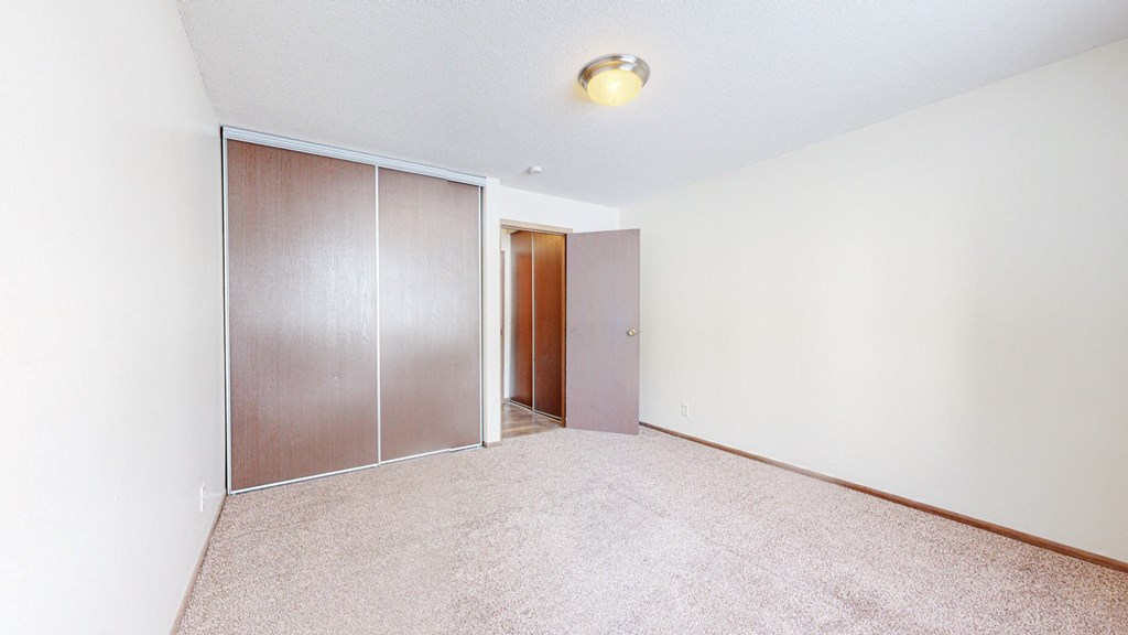 a bedroom with white walls and a sliding door to a closet