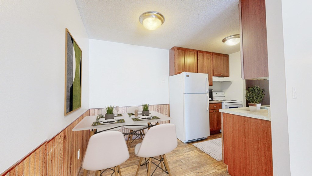 a dining area with a table and chairs and a kitchen in the background