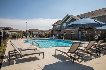 A pool surrounded by chairs and umbrellas.at The Edison at Spirit, Lakeville, MN 55044