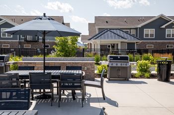 A patio with a table and chairs and an umbrella.at The Edison at Spirit, Minnesota, 55044