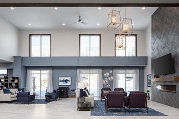 A modern living room with a grey sofa set and a fireplace.at The Edison at Spirit, Lakeville, MN