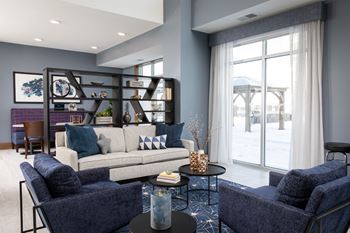 A living room with a white sofa, a blue chair, and a glass table.at The Edison at Spirit, Minnesota, 55044