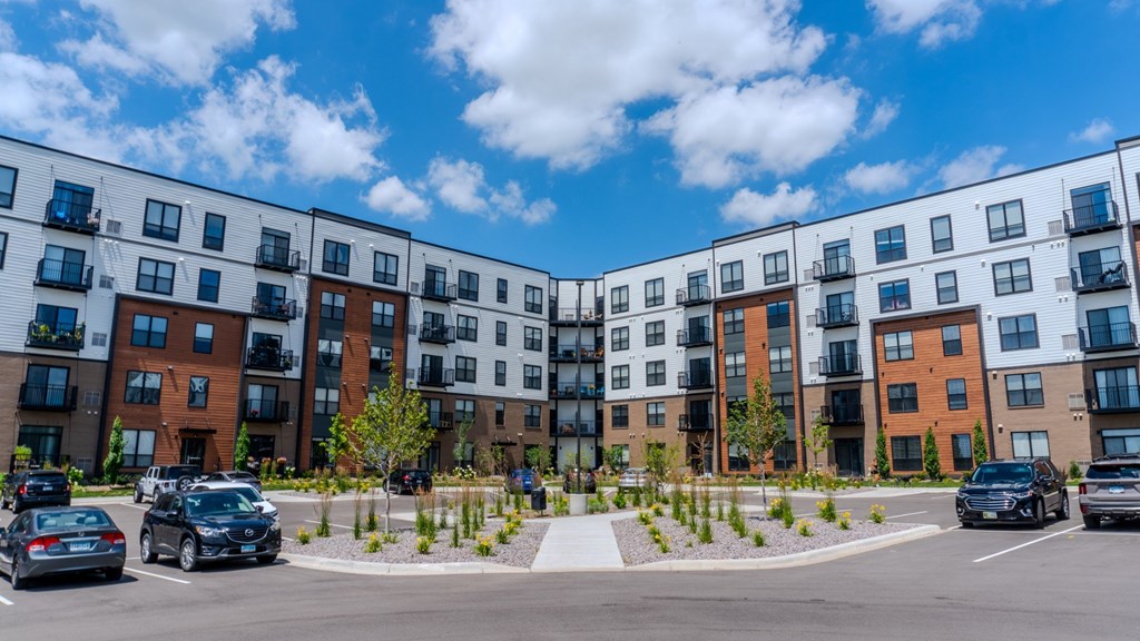 A row of modern apartment buildings with cars parked in front. at The Edison at Maple Grove, Maple Grove, MN, 55311