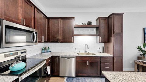 A kitchen with brown cabinets and a white backsplash.