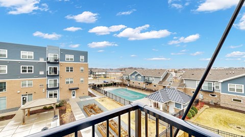A view from a balcony overlooking a pool and apartment buildings.