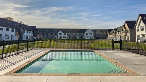 a pool with a fence around it in front of apartment buildings