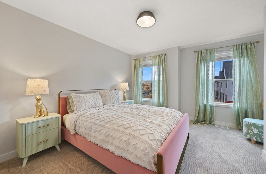 a bedroom with a pink bed and two windows