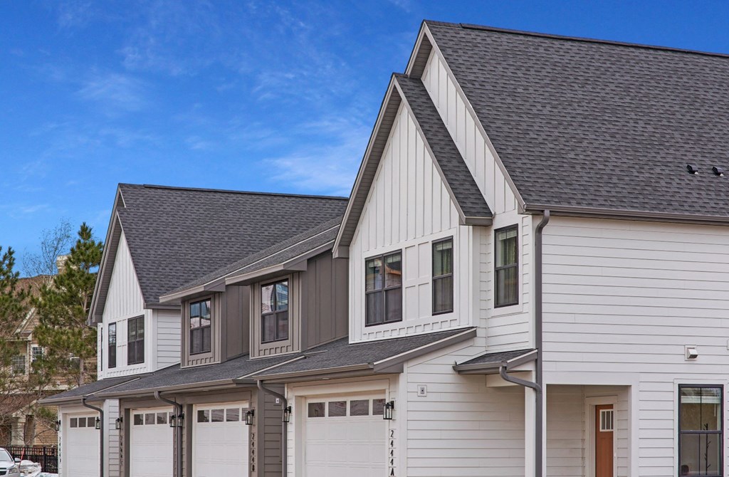 a white house with gray roof and white garage doors