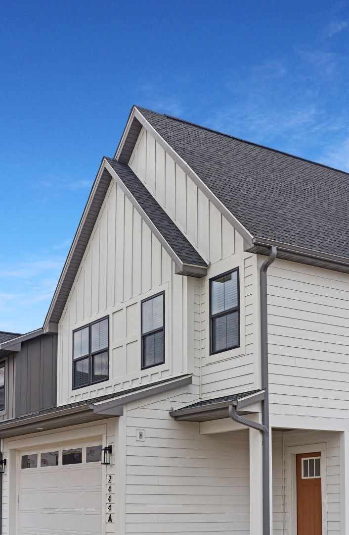 the front of a white house with a garage door