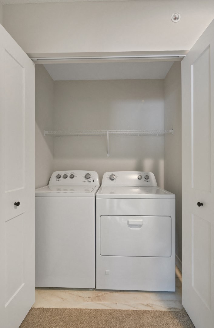 a washer and dryer in an empty laundry room with a shelf above them