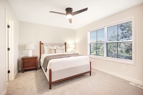 A bedroom with a bed, nightstand, and window.