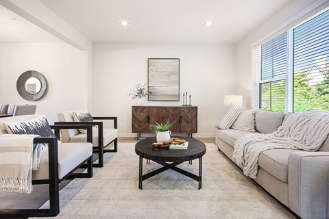 A living room with a grey couch, a coffee table, and a painting on the wall.