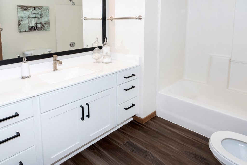 a bathroom with white cabinets and a white bathtub