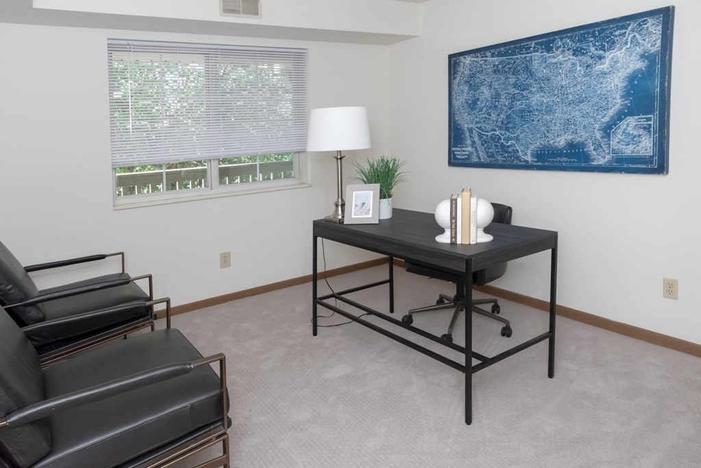 a room with a desk and chair and a large blue map on the wall