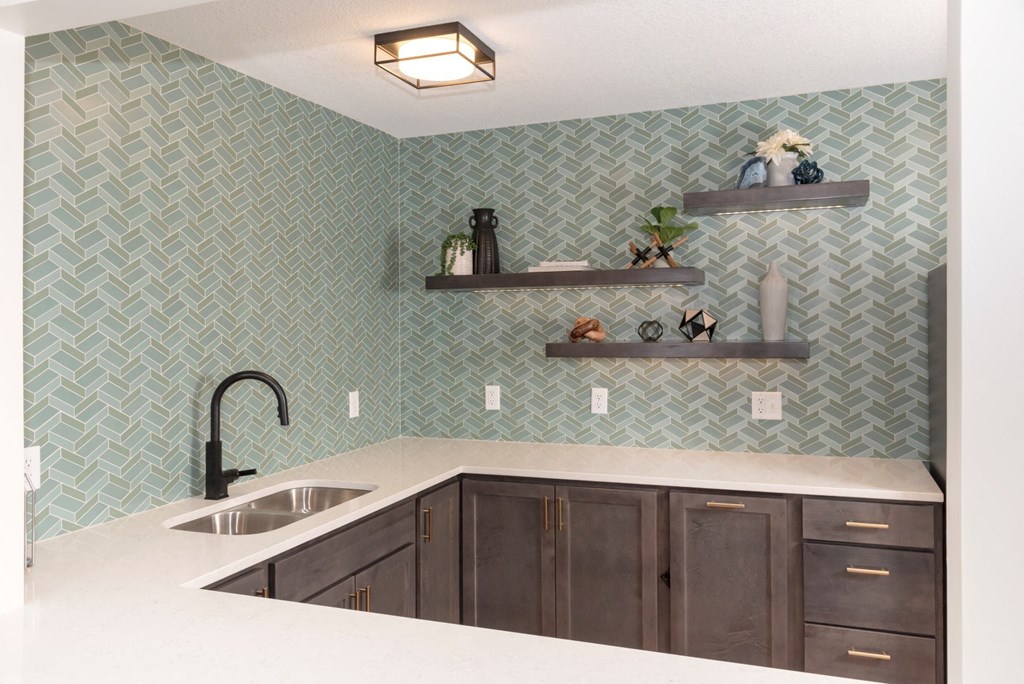 a kitchen with green tile and white countertops