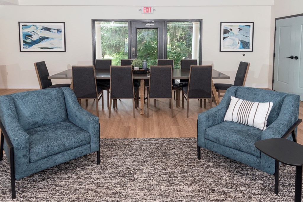 a living room with two blue chairs and a large dining table