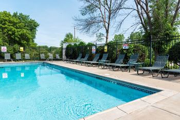 a swimming pool with chaise lounge chairs and trees in the background