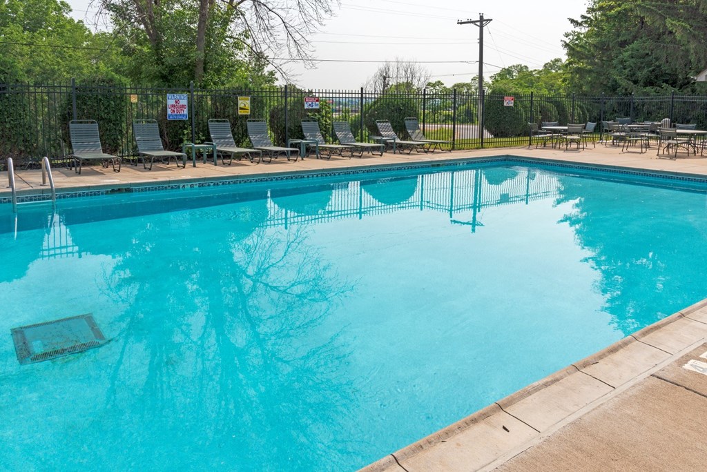 a swimming pool with chaise lounge chairs and trees in the background