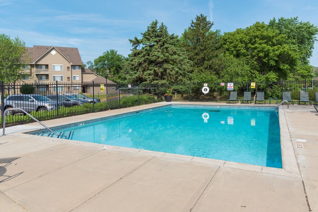 a swimming pool with a fence and trees in the background