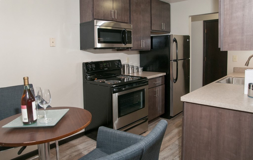 a kitchen with stainless steel appliances and a table with a bottle of wine
