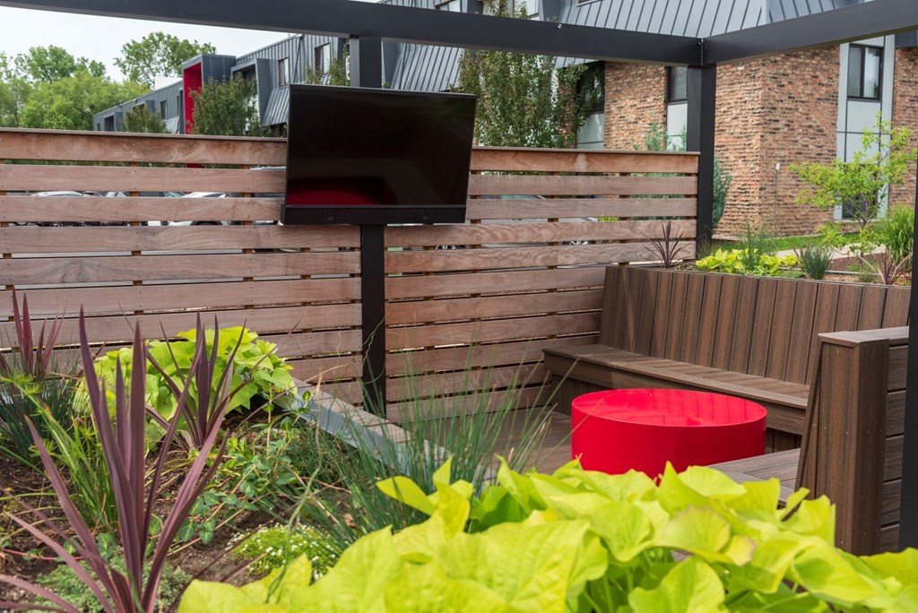 a patio with a tv and a bench in front of a brick building