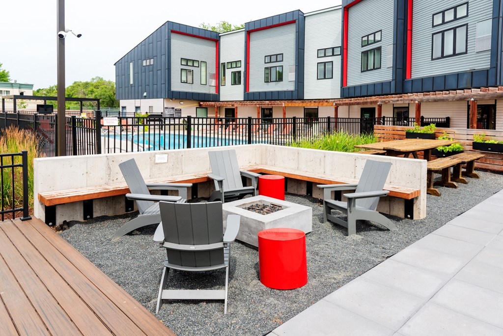 a seating area with tables and chairs in front of a row of buildings