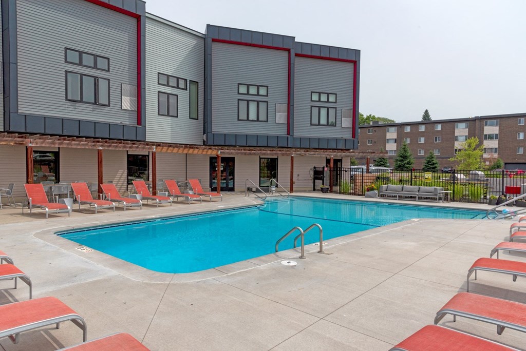 a swimming pool with chaise lounge chairs and a building in the background