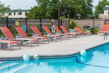 a row of red and gray chaise lounge chairs are lined up next to a swimming pool