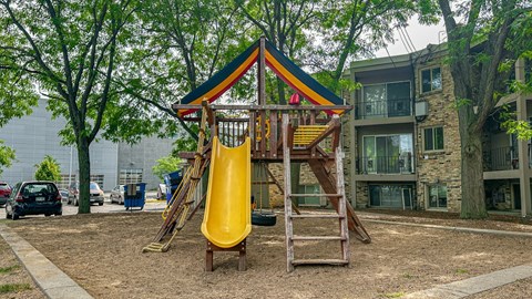 A playground with a yellow slide and a wooden structure.