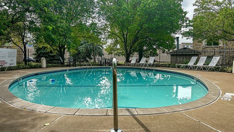 A round above ground pool with a concrete border and a pole in the middle.